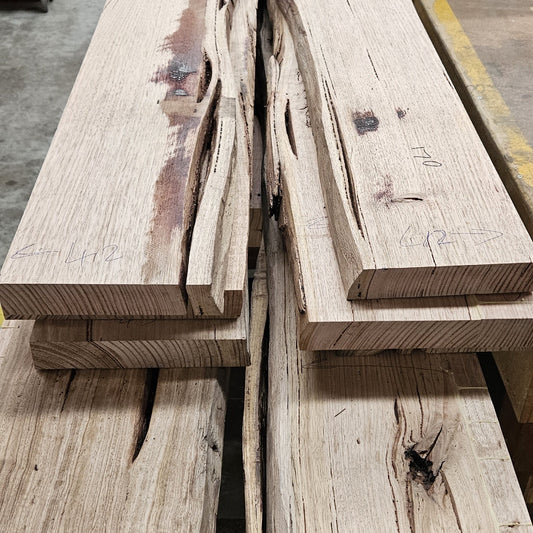 Australian Messmate Timber in a pile on a concrete floor.