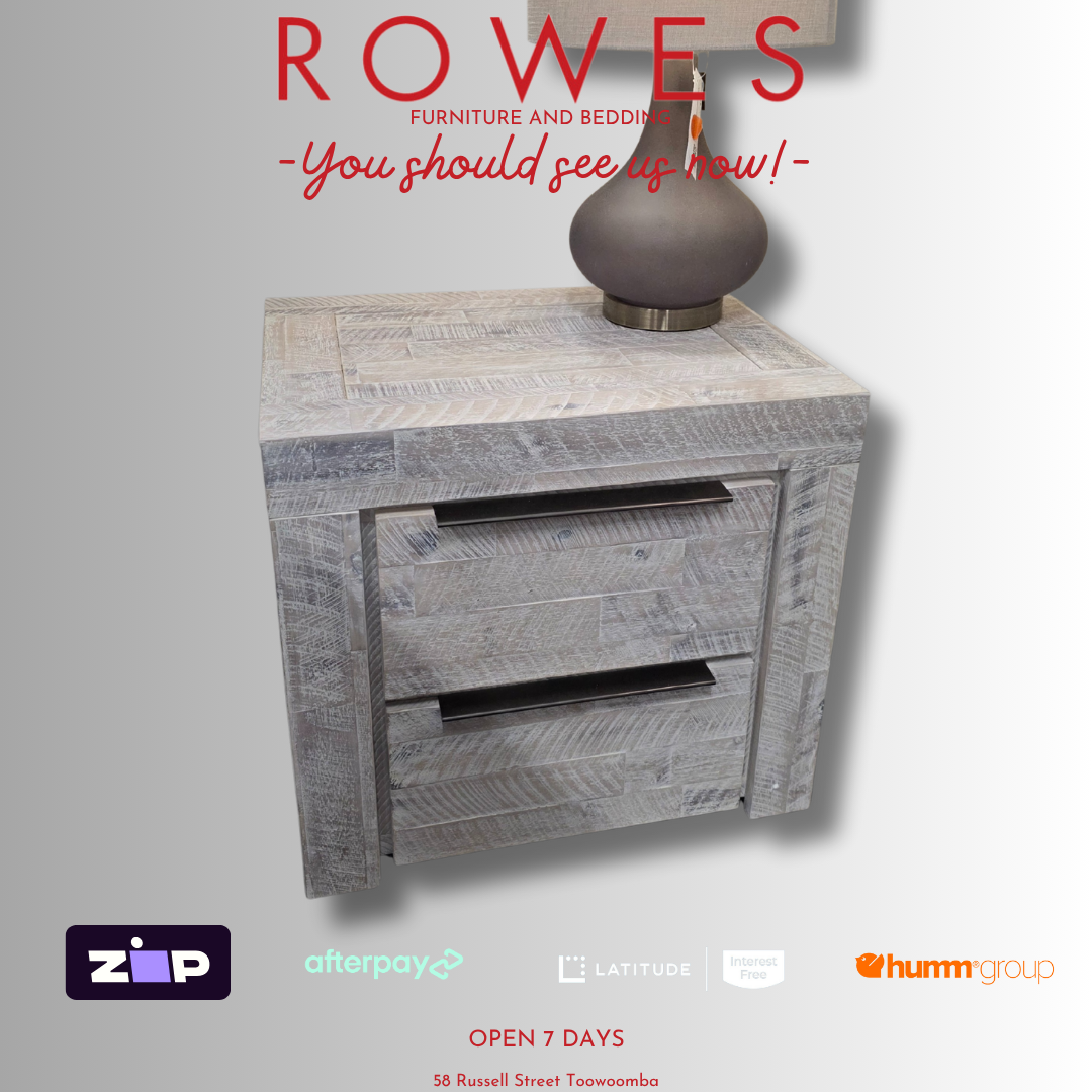 Wooden side table with a vase on top, featuring 'Rowes' furniture and bedding brand.