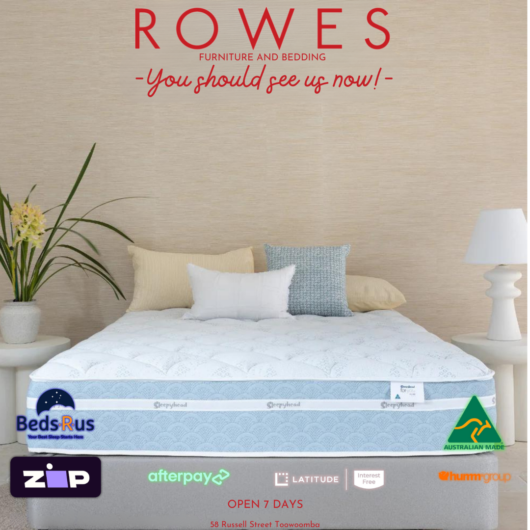 A 'For You Deluxe' mattress by Sleepyhead displayed in a bedroom setting, featuring multiple pillows, a duvet, and bedside tables with lamps.