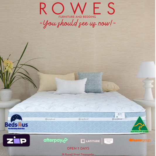 A 'For You Deluxe' mattress by Sleepyhead displayed in a bedroom setting, featuring multiple pillows, a duvet, and bedside tables with lamps.
