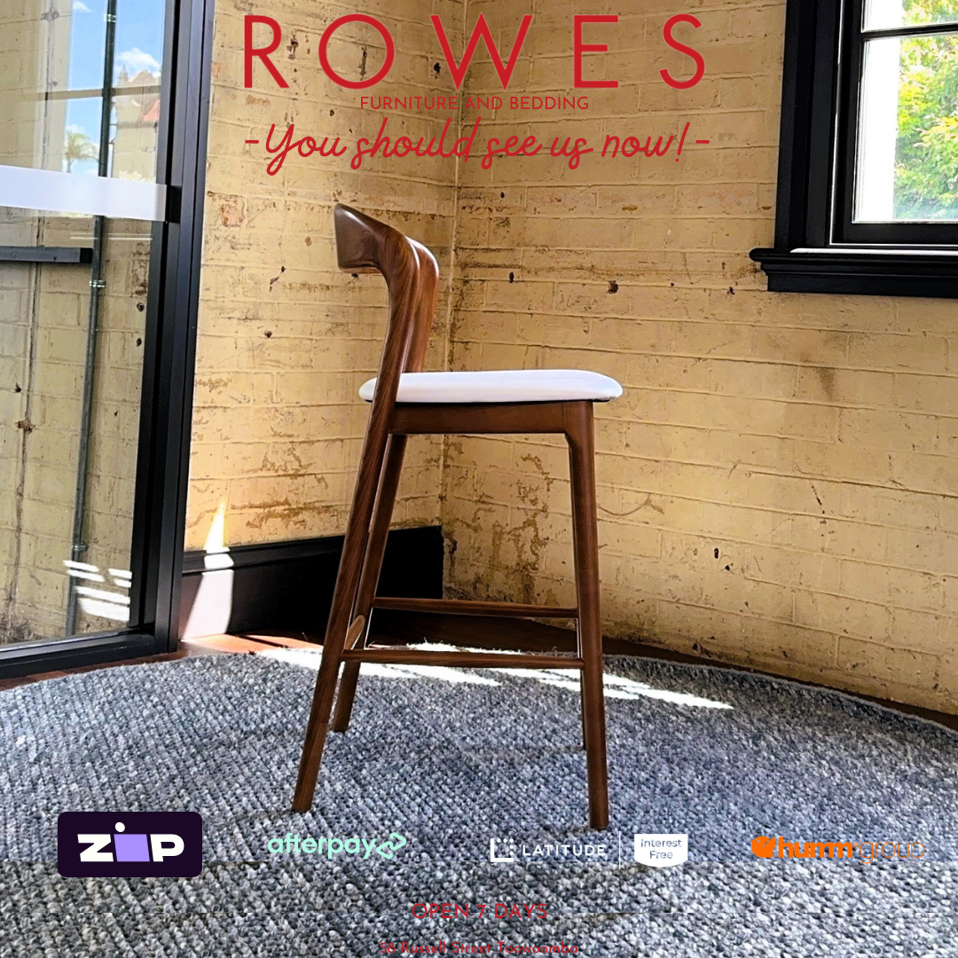 Wooden chair in a room with a brick wall and large window, featuring the brand 'Rowes'.