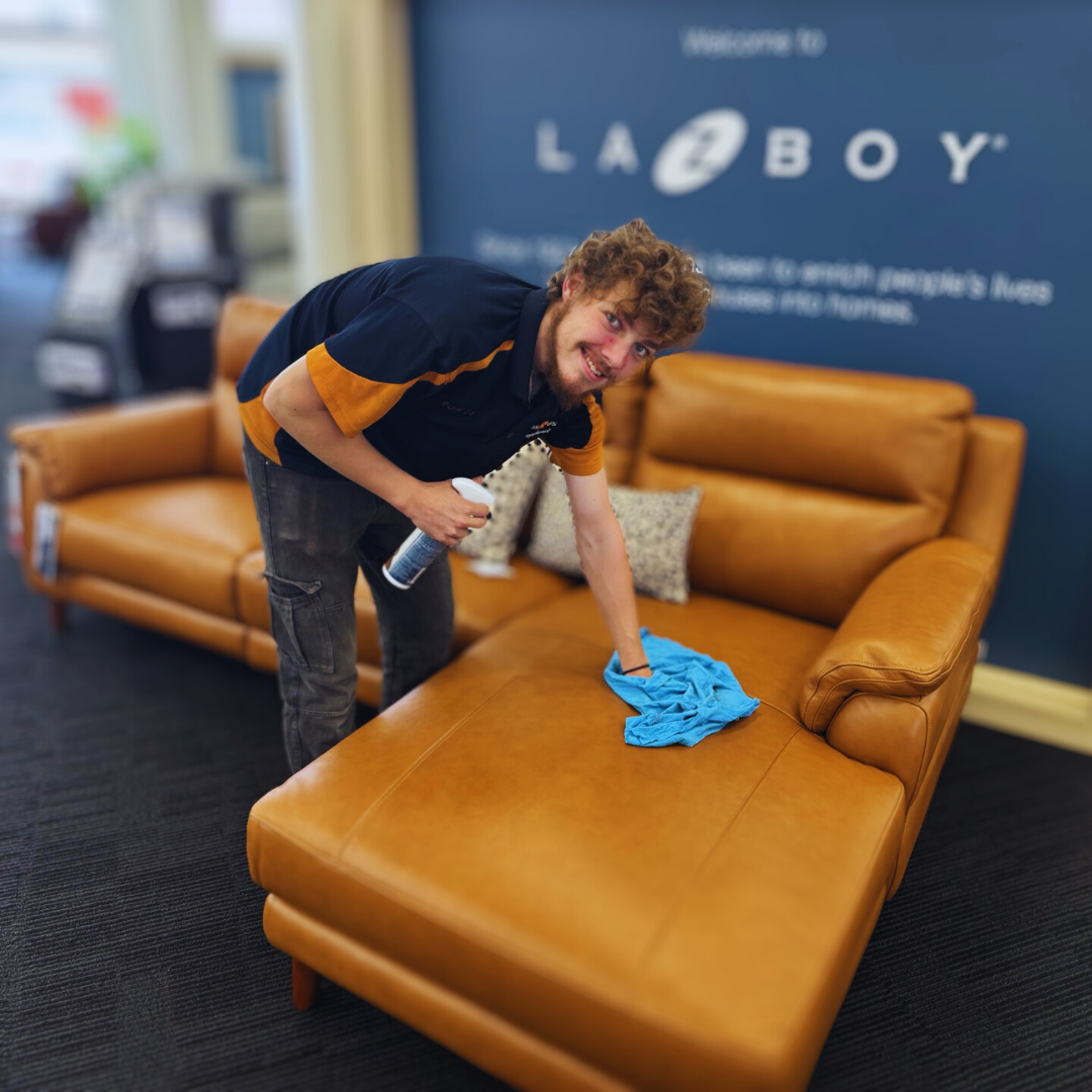 Man cleaning leather with LaZboy logo in the background.