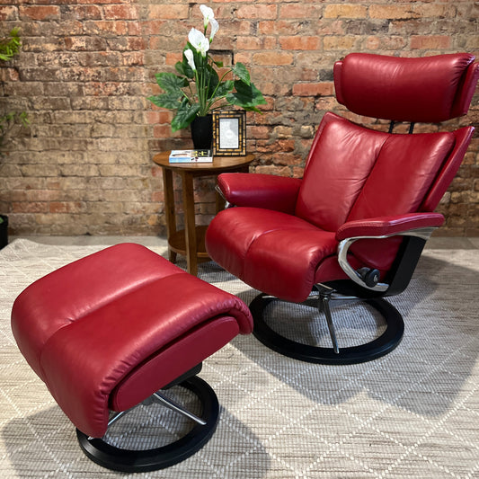 A red and black leather recliner chair set against a brick background