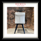 A framed product photograph of a modern dining chair with a white upholstered backrest and dark blue angled legs, set against a rustic brick wall. The image is presented in a white mat and a thick black frame, with the brand name 'ROWES FURNITURE & BEDDING' printed at the top.