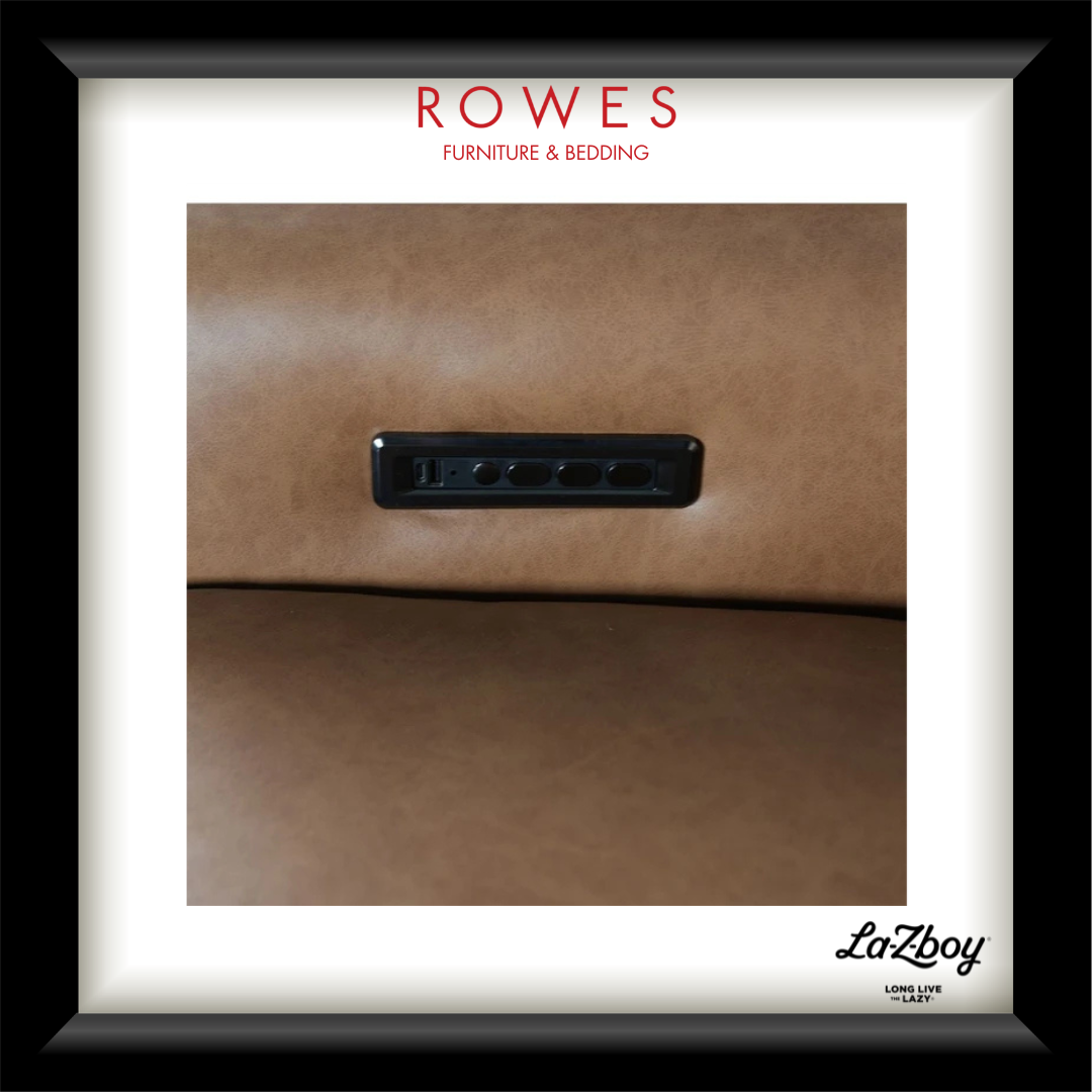A framed close-up photograph of a brown upholstered surface with a black rectangular control panel inset, presented with a white mat and black frame. Visible text includes 'ROWES FURNITURE & BEDDING' at the top and 'LaZboy' at the bottom right.