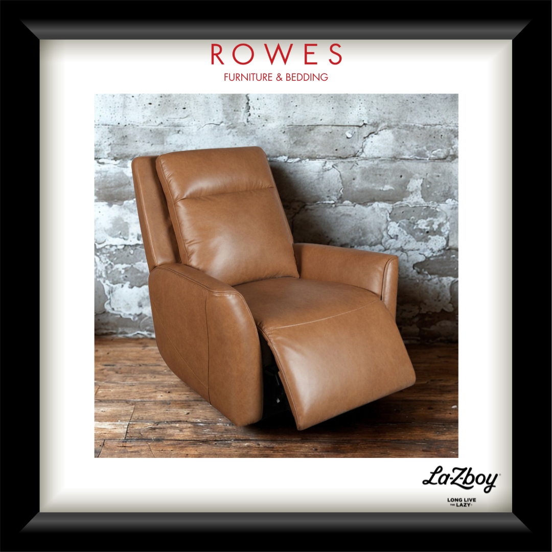 A framed promotional print featuring a tan leather recliner chair in front of a distressed gray brick wall and wooden floor. The print includes the text 'ROWES FURNITURE & BEDDING' at the top and 'LaZboy' at the bottom, set within a white mat and black frame.