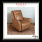 A framed product display featuring a tan leather recliner chair in a styled room scene with a white brick wall and patterned rug. The frame includes the text 'ROWES FURNITURE & BEDDING' at the top and 'LaZboy' at the bottom right.