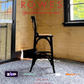 Black wooden chair in a room with wooden walls and large windows, featuring the brand 'Rowes'.
