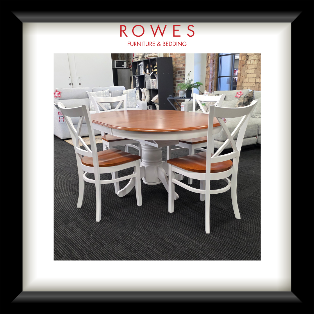 A white dining table surrounded by matching chairs. The top of the dining table and the seats of the chairs are all natural timber coloured. The Rowes branding is prominent. 