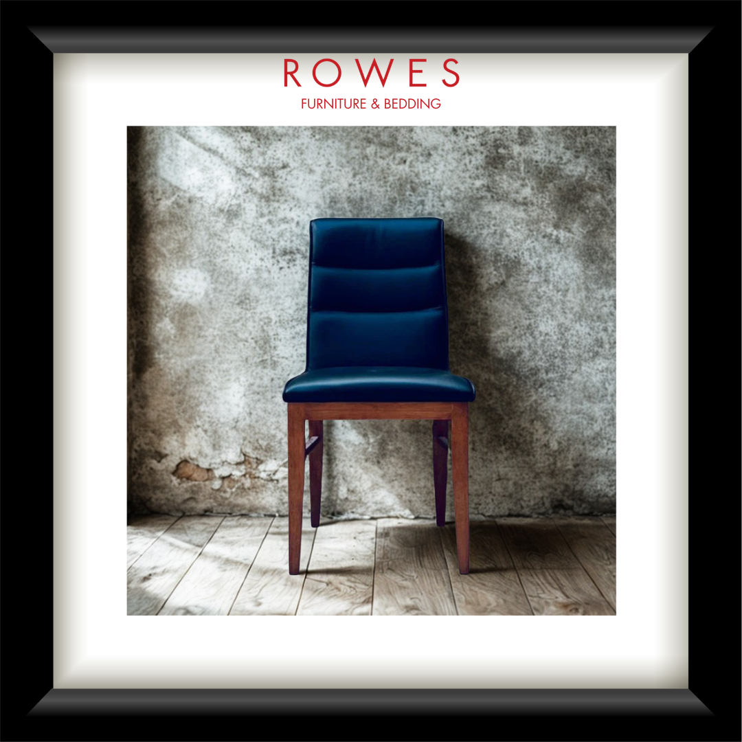 A framed print or poster featuring a dark blue upholstered wooden chair against a textured concrete wall and wood floor. The print is matted with a white border and enclosed in a black frame.