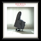 Gray recliner chair in a room with white curtains, branded as Rowes Furniture & Bedding.