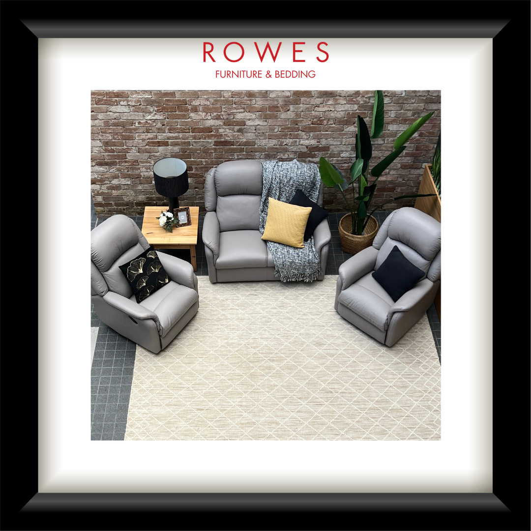 Living room setup with gray chairs and a small table against a brick wall, featuring Rowes Furniture & Bedding branding.