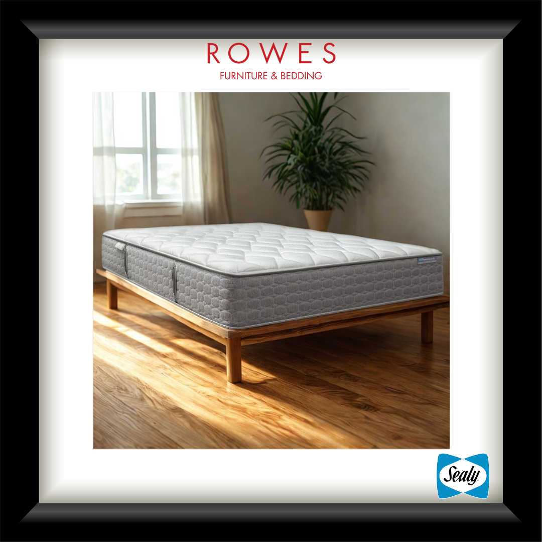 Gray mattress on a wooden bed frame in a room with a plant and window, branded as Rowes Furniture & Bedding.