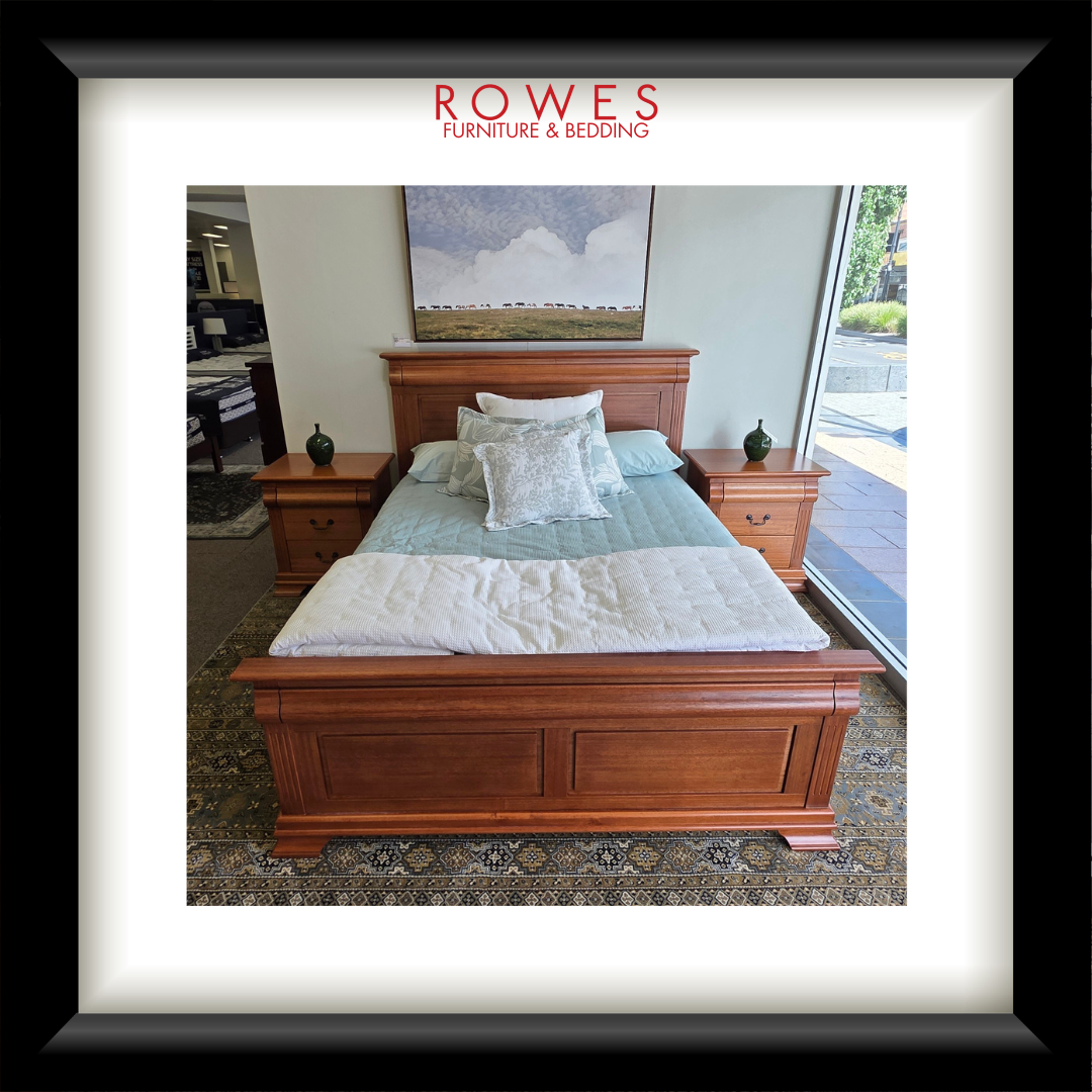 Wooden bed with bedding in a room setting, featuring Rowes Furniture & Bedding logo.