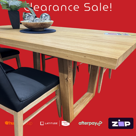 Wooden dining table with black chairs on a red background with clearance sale text