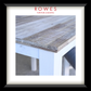 A framed product display featuring a close-up photograph of a rustic wooden tabletop corner with a white painted frame, surrounded by a white mat and a black frame. The brand name 'ROWES FURNITURE & BEDDING' is printed in red at the top.