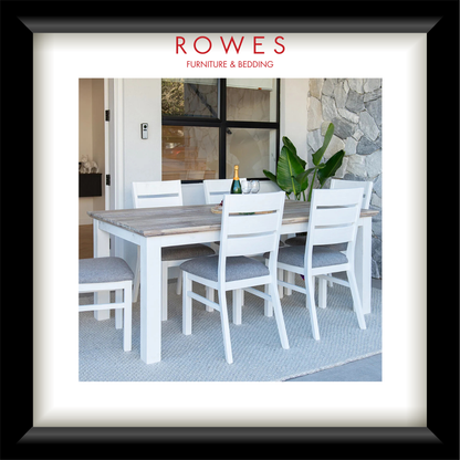 A framed catalog-style print from Rowes Furniture & Bedding, showing a dining table and chairs in a bright interior setting. The print is matted with a wide white border and enclosed in a black frame.