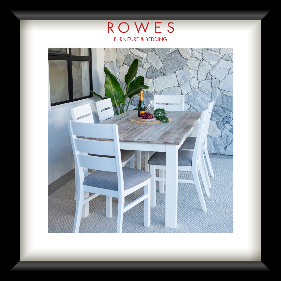 A framed catalog-style print from ROWES Furniture & Bedding, showing a dining table and chairs in a bright interior setting. The print is matted with a wide white border and enclosed in a thick black frame.