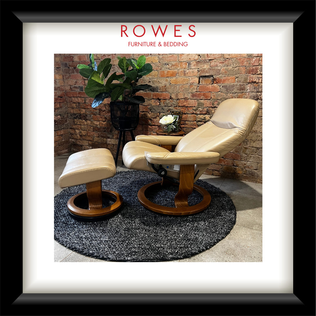 Beige recliner chair and ottoman with a plant and small table against a brick wall, branded 'Rowes Furniture & Bedding'.