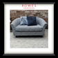 Gray floral-patterned sofa with blue pillows against a brick wall, featuring 'Rowes Furniture & Bedding' logo.