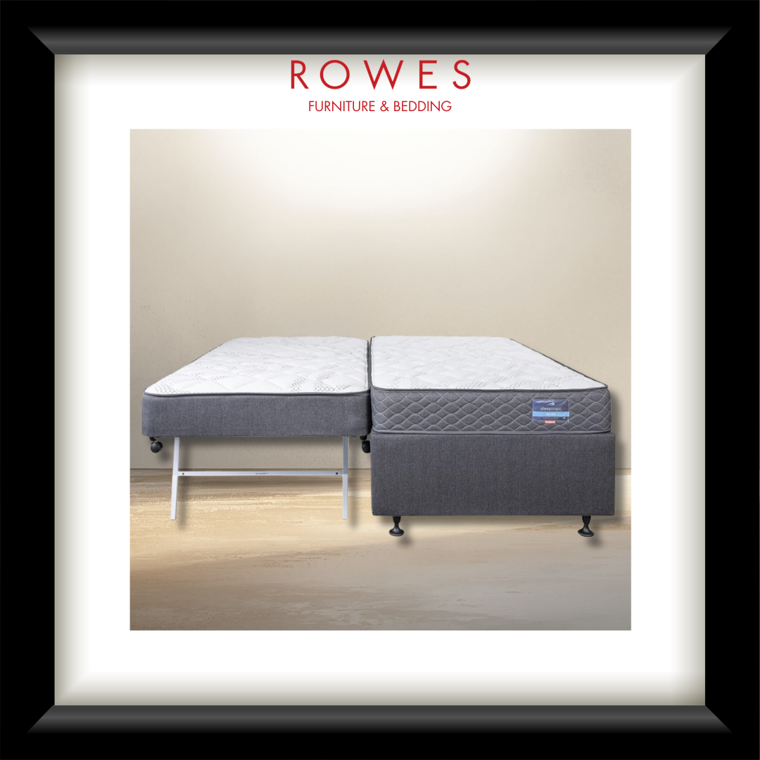 A framed product photograph of a Rowes double mattress setup, featuring a gray upholstered base and two mattresses on a white and light wood floor, set against a beige wall. The image is presented in a black frame with a white mat and the brand name 'ROWES FURNITURE & BEDDING' printed at the top.
