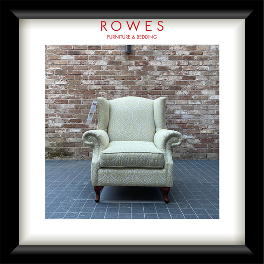 Decorative armchair in front of a brick wall with 'Rowes Furniture & Bedding' branding.