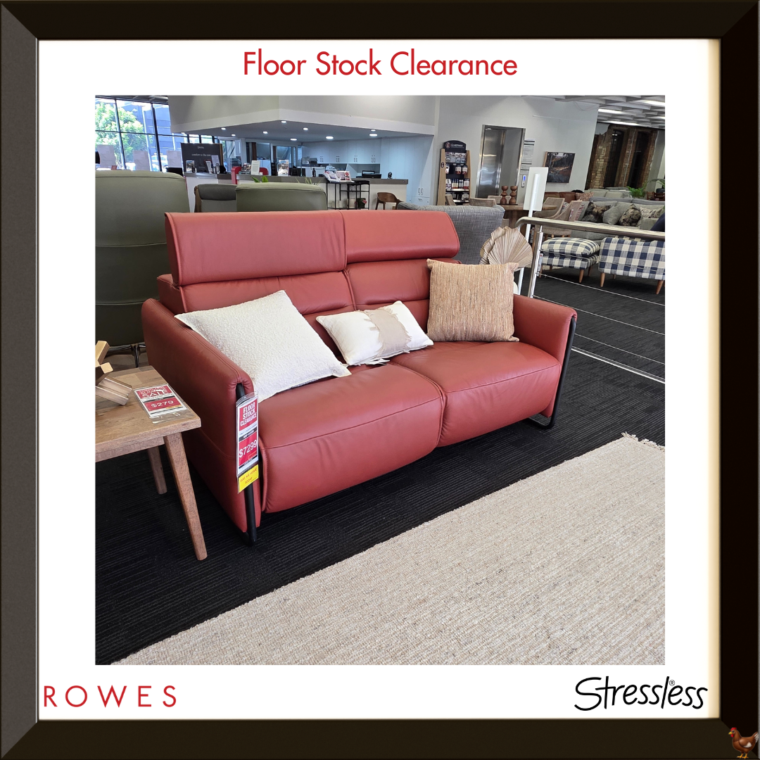 Red sofa with cushions in a showroom setting, featuring 'Rowes' and 'Stressless' branding.