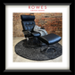 Black leather recliner chair with ottoman on a textured rug against a brick wall, branded 'Rowes'.