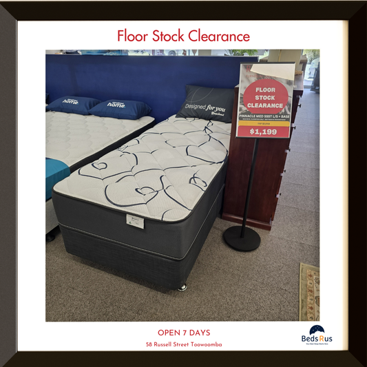 Mattress on display with 'Floor Stock Clearance' sign in a store.