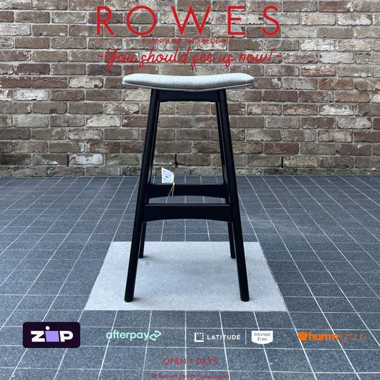 Black bar stool on a gray floor with a brick wall background, featuring the brand 'Rowes'.