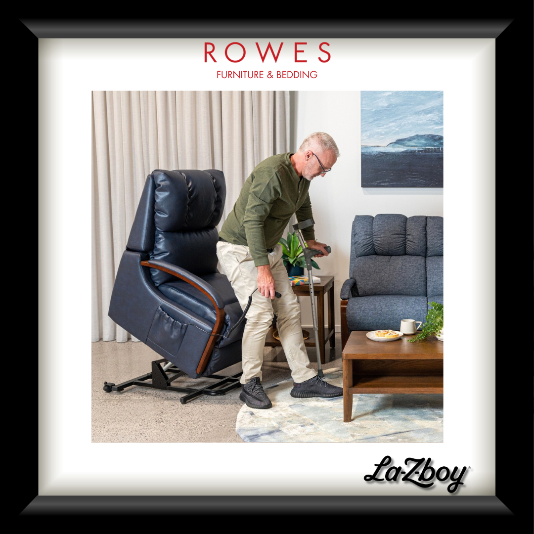 Man adjusting a blue recliner chair in a living room with 'Rowes Furniture & Bedding' and 'La-Z-Boy' branding.