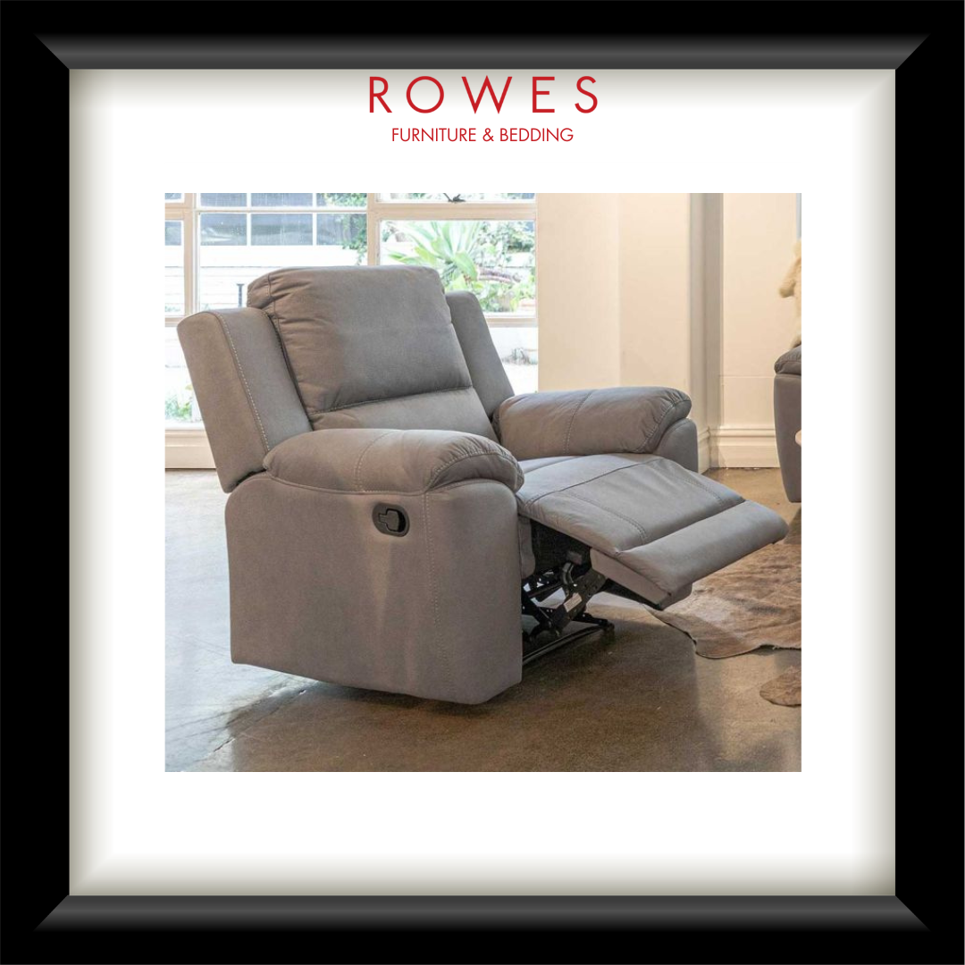 A light gray upholstered recliner chair shown inside a white mat and black frame, with the brand name ROWES FURNITURE & BEDDING printed at the top. The recliner is positioned in a real indoor room with a visible window, floor, and rug.