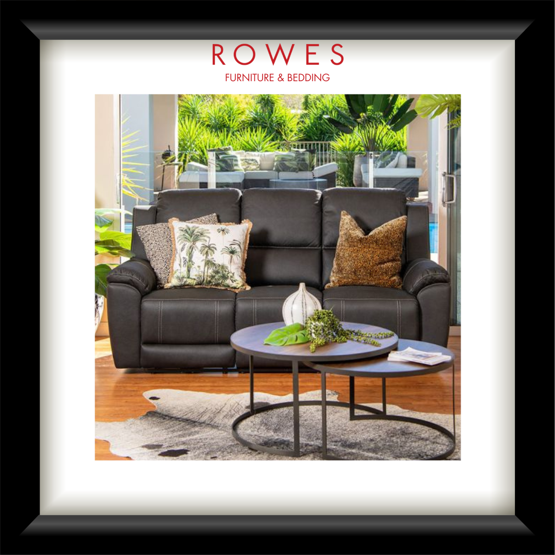 A framed catalog-style image showing a dark brown leather reclining sofa in a modern living room setting, with two decorative pillows, a round coffee table, and the text 'ROWES FURNITURE & BEDDING' at the top.