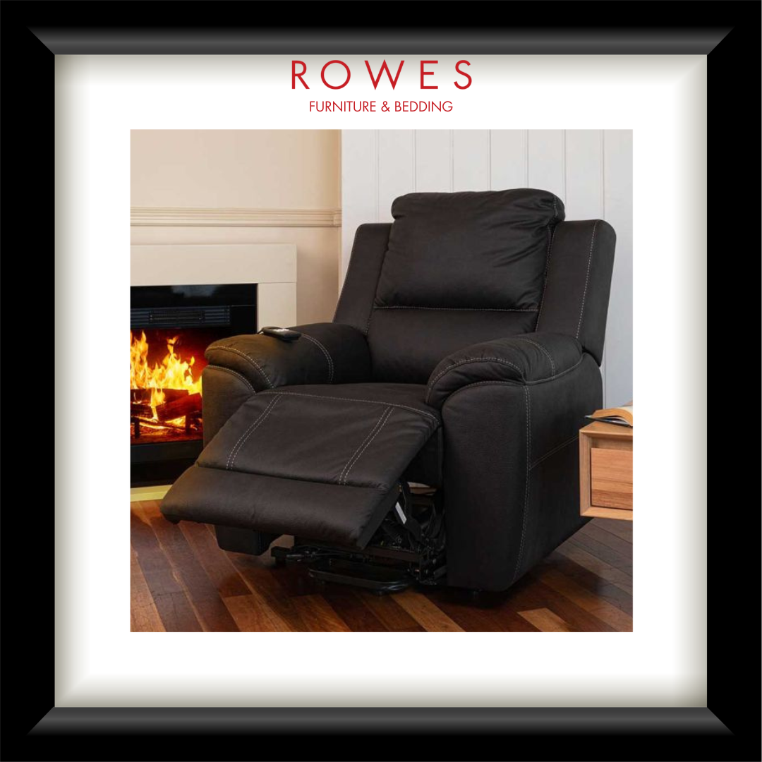 A framed product photograph of a black leather recliner chair in a living room setting with a fireplace, presented in a black frame with a white mat. The brand name 'ROWES FURNITURE & BEDDING' is printed at the top of the photo.