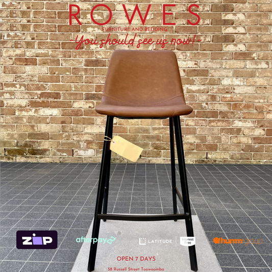 Brown leather stool with black legs on a gray floor against a brick wall, with 'ROWES' branding above.