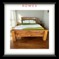 A large bed with green and white linens in a large bedroom. The image features the Rowes branding