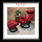 Red leather recliner chairs in a room with a brick wall and a plant.