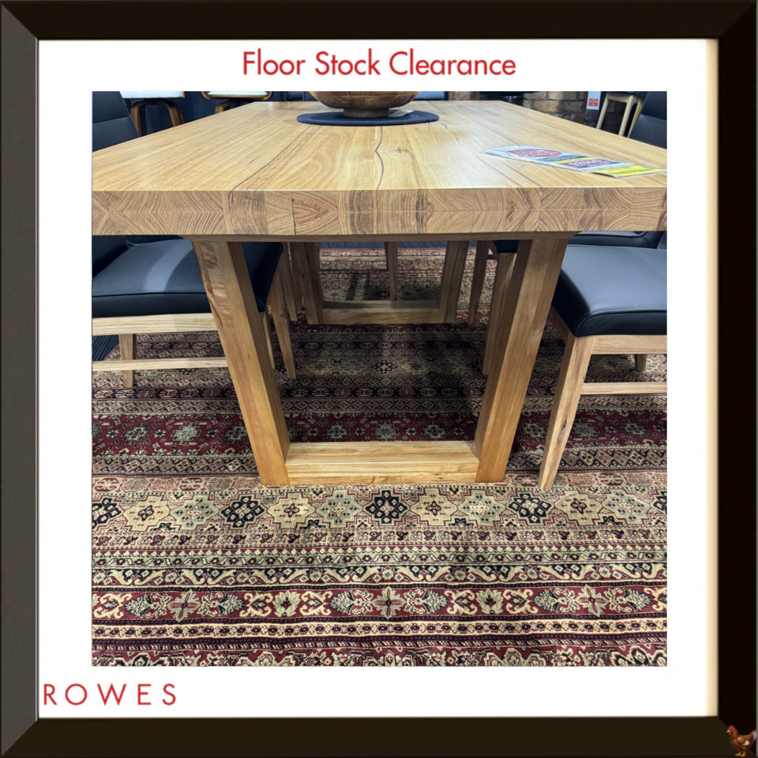 The image shows a photo in a frame of a dining table on a colourful rug, surrounded by leather chairs and featuring the Rowes branding.