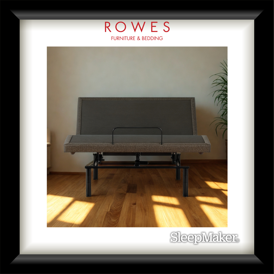 Gray sofa bed in a room with wooden floor and plant, branded as 'Rowes Furniture & Bedding'.