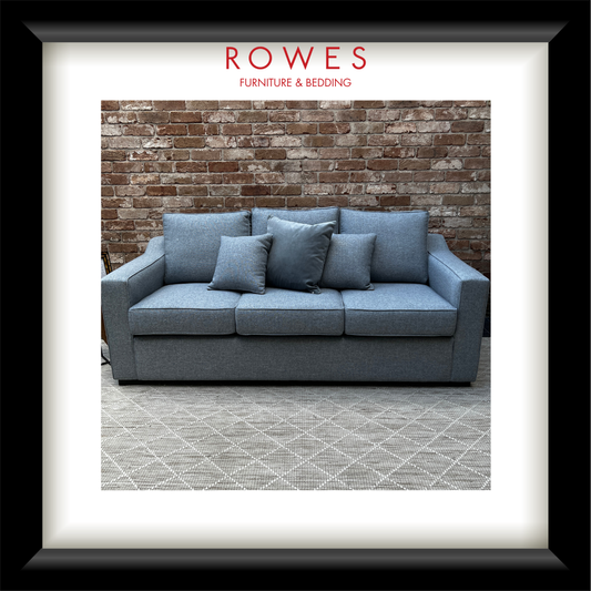 Blue sofa with cushions against a brick wall, featuring 'Rowes Furniture & Bedding' logo.