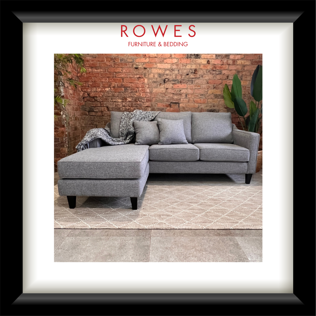 Gray sofa with a matching ottoman against a brick wall, featuring 'Rowes Furniture & Bedding' branding.