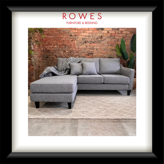 Gray sofa with a matching ottoman against a brick wall, featuring 'Rowes Furniture & Bedding' branding.