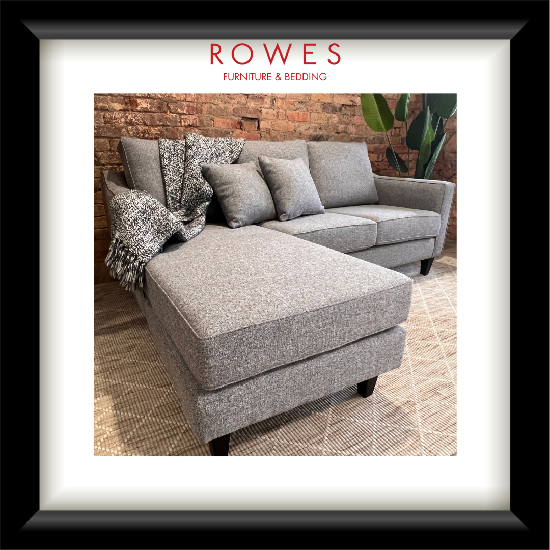 Gray sectional sofa with pillows and a blanket on a textured floor, branded as Rowes Furniture & Bedding.