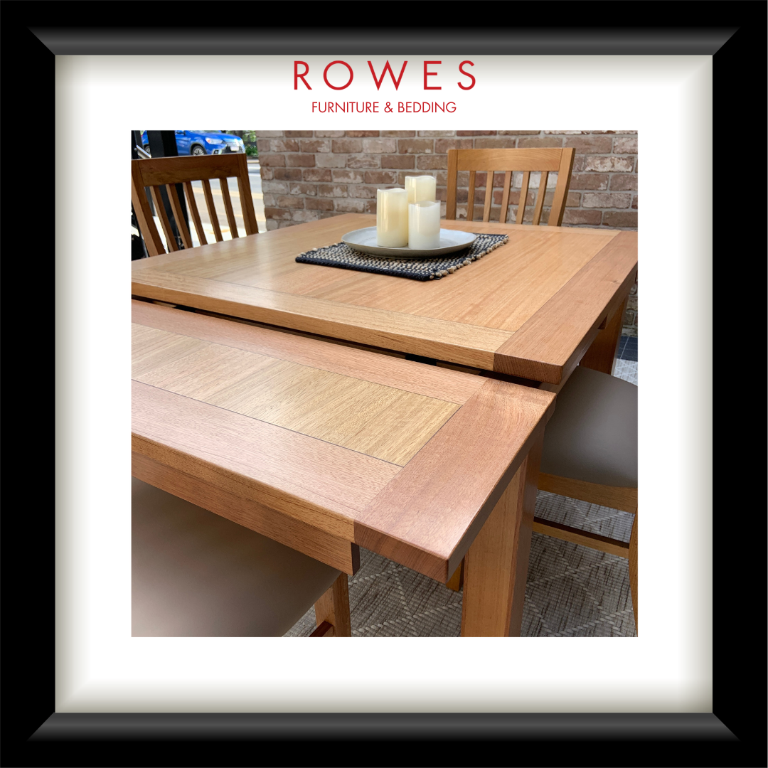 A framed product photo of a wooden dining table with matching chairs, shown inside a black frame with a white mat. The top of the mat features the text 'ROWES FURNITURE & BEDDING'.