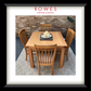 A framed product display featuring a wooden dining table and four matching slat-back chairs on a patterned rug, with a brick wall background. The image is presented inside a white mat and a thick black frame, with the brand name 'ROWES FURNITURE & BEDDING' printed at the top of the photo.