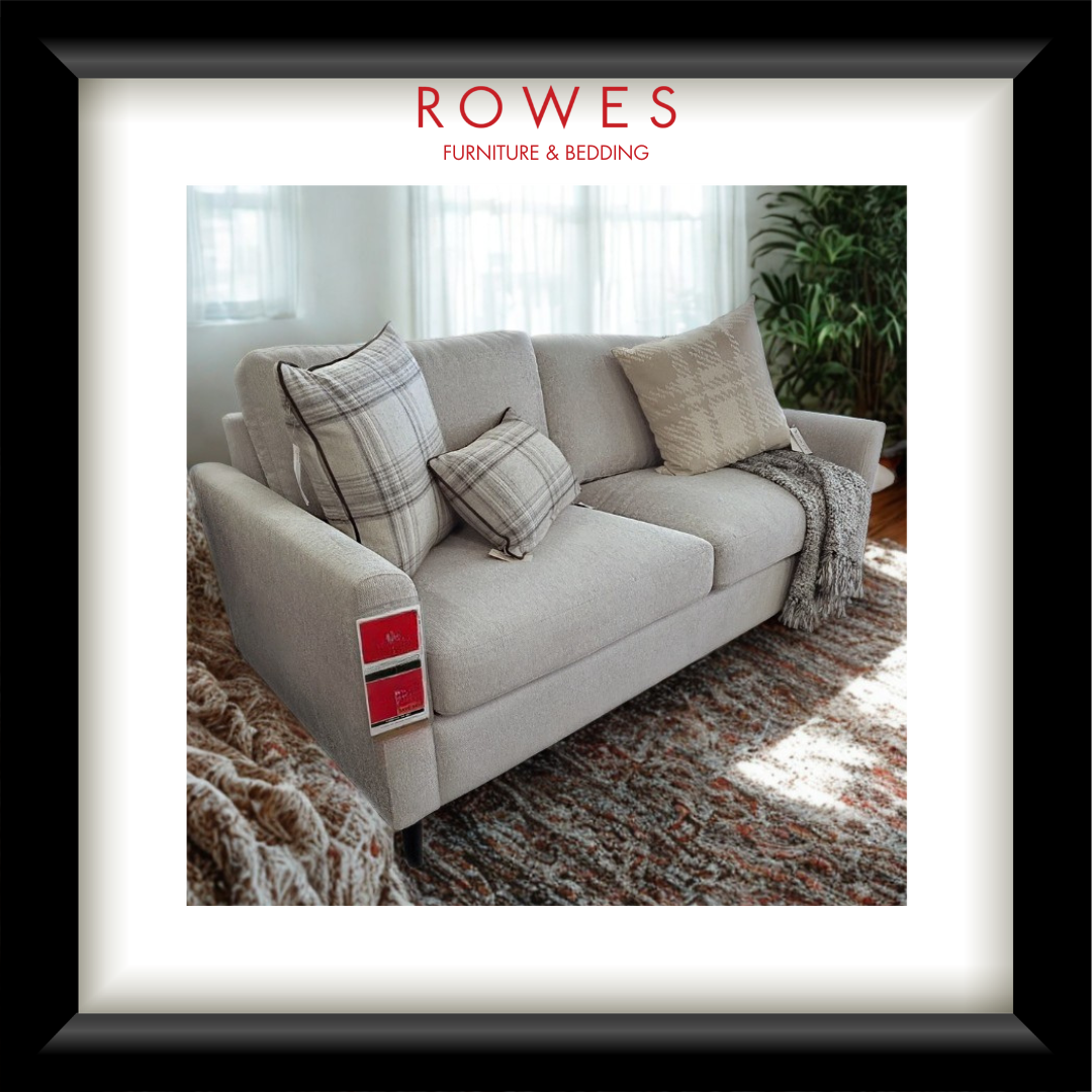 Gray sofa with patterned cushions on a textured rug, featuring Rowes Furniture & Bedding logo.