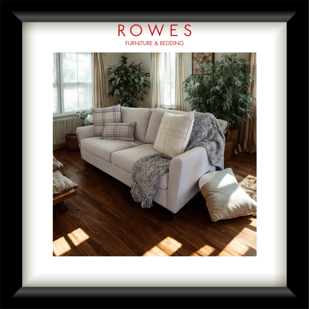 Living room with a white sofa, cushions, and a blanket, featuring Rowes Furniture & Bedding branding.