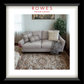 Gray sofa with decorative pillows on a patterned rug in a room with a plant and framed picture, featuring 'Rowes Furniture & Bedding' logo.