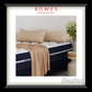Bed with beige bedding and pillows, featuring Rowes Furniture & Bedding logo.