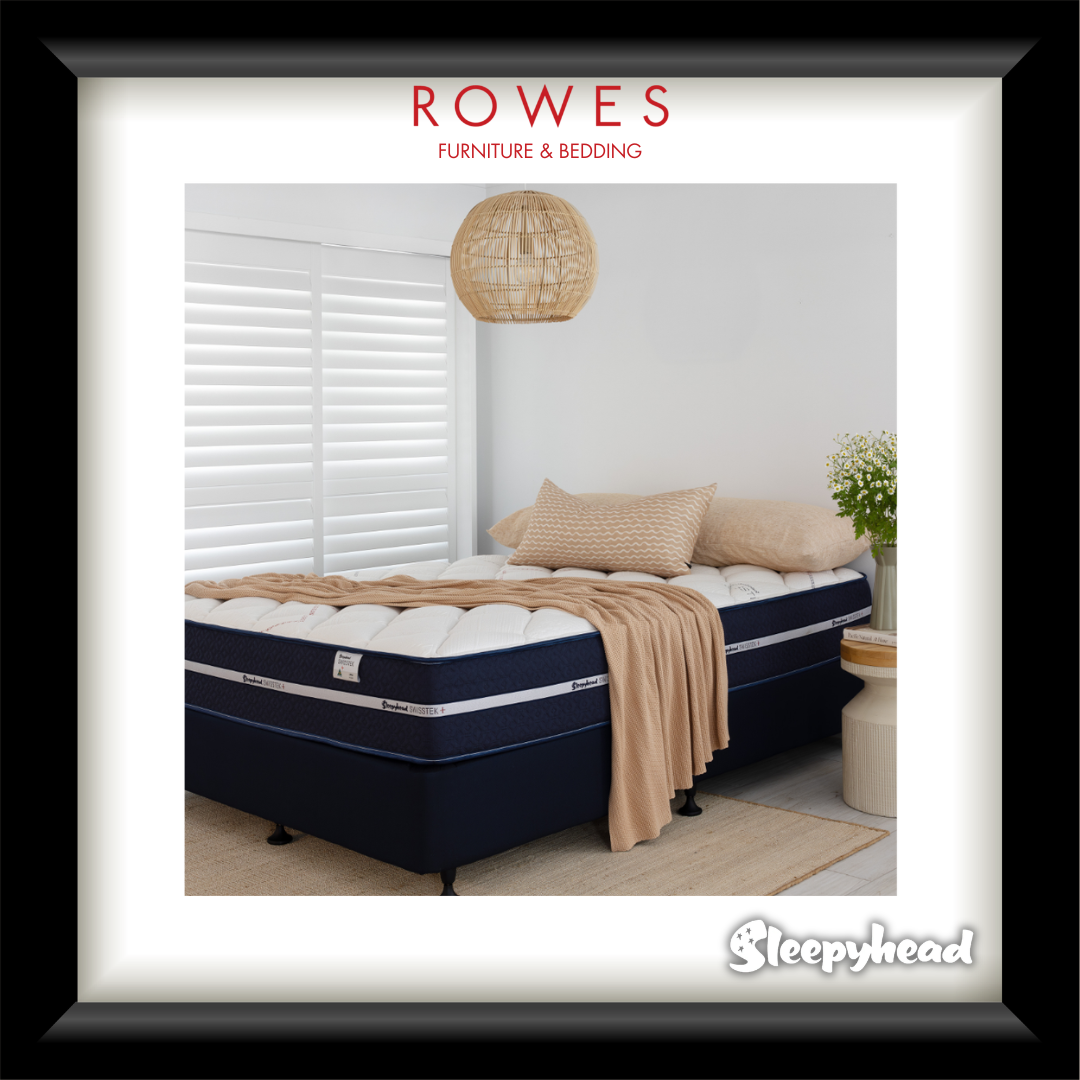 Navy blue mattress with beige bedding in a bedroom setting, featuring Rowes Furniture & Bedding branding.